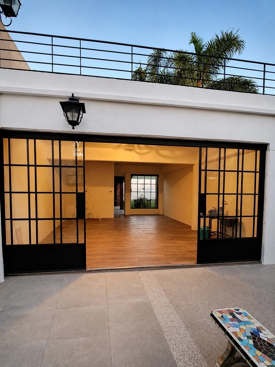 Cerramiento corredizo de hierro y vidrio abierto hacia un patio