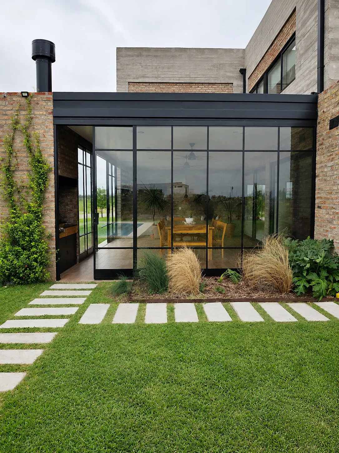 Cerramiento corredizo de hierro y vidrio en una vivienda contemporánea con jardín
