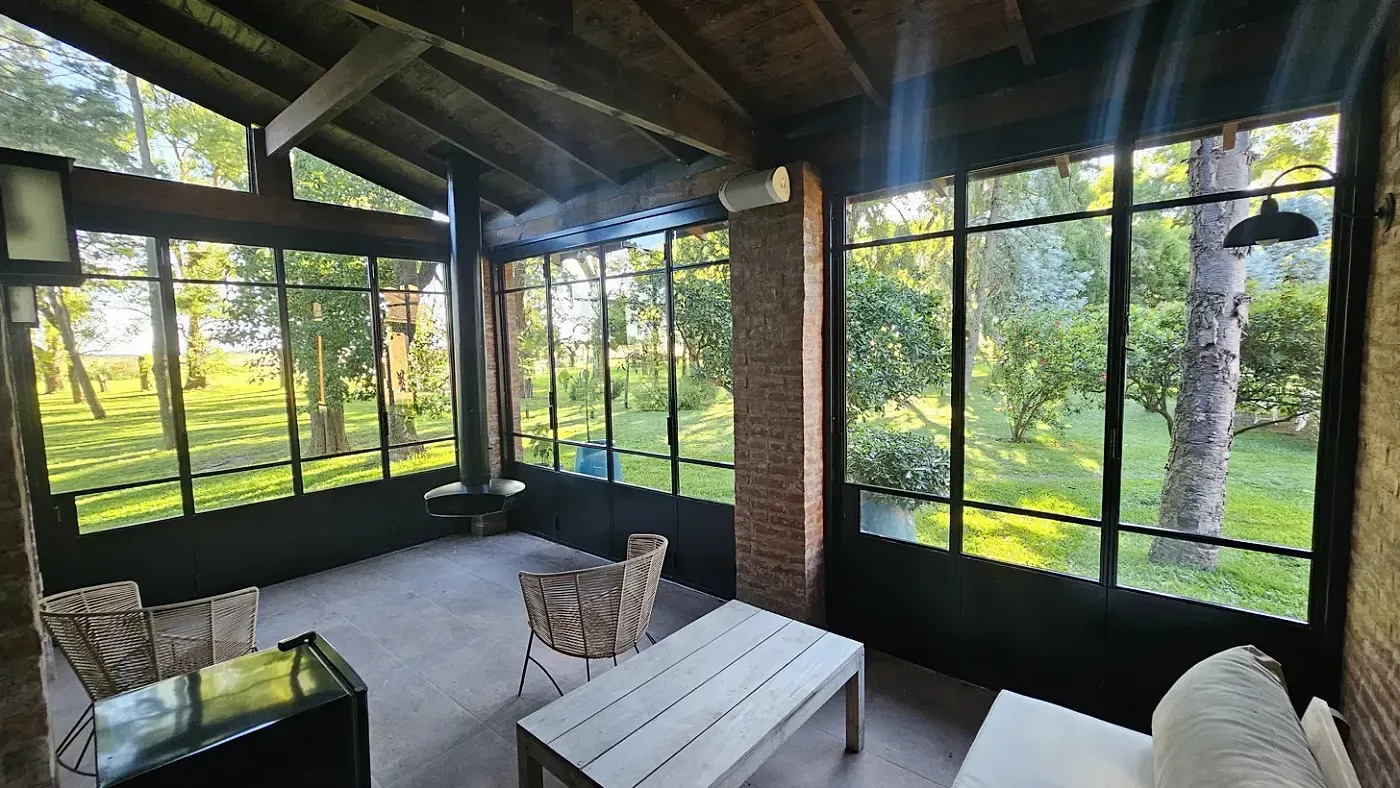 Interior de galería con cerramiento plegable de hierro y vidrio y vista al parque